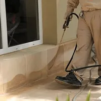 General pest control technician spraying exterior perimeter around a home in Buffalo, NY